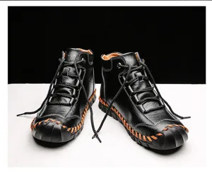 Detailed view of handmade black leather work boots with orange stitching