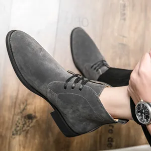 Eleganti stivali da uomo in pelle scamosciata grigia stile British su pavimento in legno