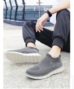 Vue de chaussures de marche grises tricotées et respirantes pour hommes sur sol en pierre