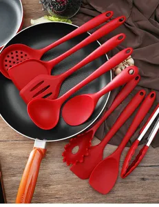 Primer plano de utensilios de cocina de silicona roja dispuestos en una sartén negra