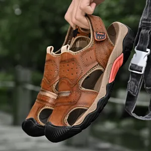 Detailed view of handmade brown leather outdoor sandals for men held in hand.