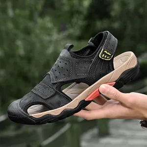 Lightweight black leather men's outdoor sandals held in a hand with a forest backdrop.