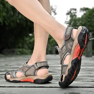 Side view of men's leather outdoor sandals with orange accents on wooden boardwalk