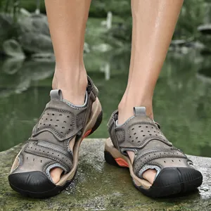 Close-up of men's genuine leather outdoor sandals being worn on a wet rock near a pond