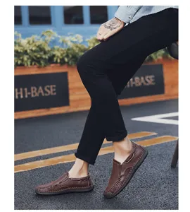 Primo piano di mocassini da uomo in pelle marrone indossati con pantaloni neri.