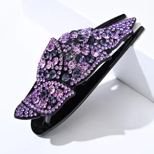 Vista detallada de pinza para el pelo con pedrería violeta para peinado elegante.