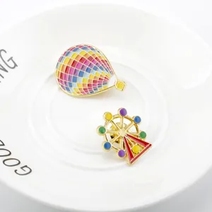 Close-up detail of colorful enamel hot air balloon and ferris wheel pins on a white plate