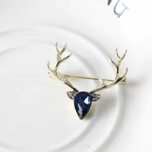 Primo piano dettagliato di una elegante spilla a forma di cervo dorato con gemma blu.