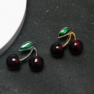Gros plan détaillé de broches cerises rouges vibrantes avec tiges métalliques et feuilles.