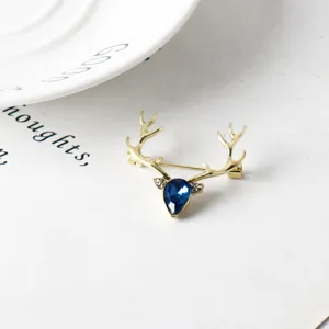 Vista dettagliata della spilla cervo dorata con cristallo blu e strass per abito elegante.