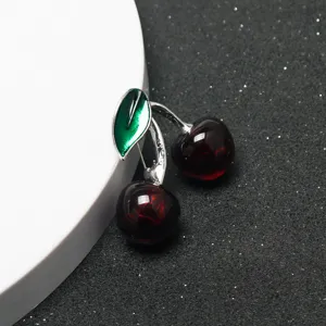 Gros plan d'une broche cerise créative avec fruits rouges et feuille verte, détail stylé.