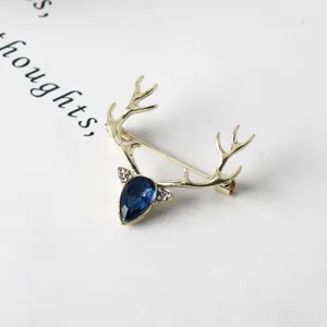 Spilla a corna di cervo dorata con cristallo a goccia blu e strass per abito elegante