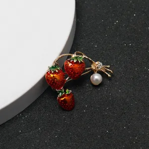 Close-up detail of the red strawberry brooch showcasing sparkling rhinestones and pearl accent.