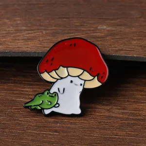 Primo piano dettagliato di una simpatica spilla smaltata con fungo e rana verde.