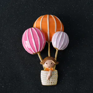 Close-up detail of cute hot air balloon little girl enamel brooch pin for bags and suits.