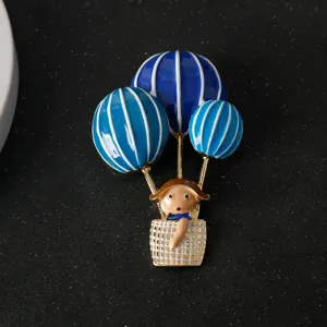 Close-up detail of the blue and white hot air balloon cartoon girl brooch accessory.