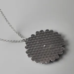 Detailed view of the metal alloy rotatable flower pendant necklace with fine silver chain.