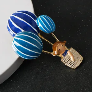Close up detail of the blue and white hot air balloon brooch, featuring gold trim enamel.