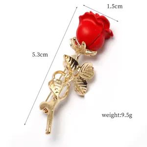 Close-up detail shot of the red rose brooch showing its exquisite gold-plated stem design.
