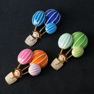 Detail shot of cute hot air balloon brooches with little girl figures, metal enamel.