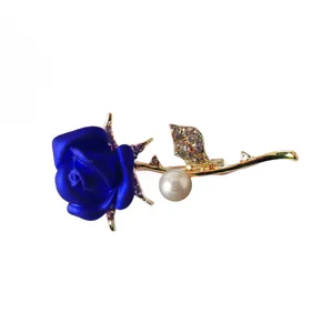 Detailed close-up of a glamorous blue rose rhinestone and pearl brooch with shiny gold stem.