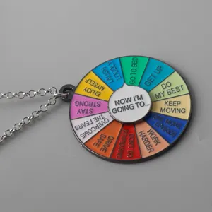 Close-up detail of the colorful spinner wheel pendant necklace showing engraved decision text.
