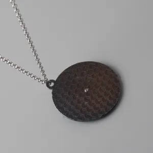 Silver chain necklace with a dark geometric pattern round spinning pendant for daily wear.
