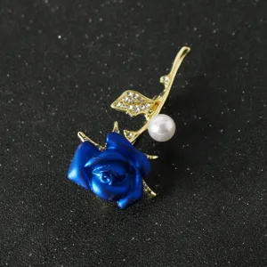 Close-up detail of blue rose brooch with rhinestone leaves and pearl accent for elegant outfit styling.
