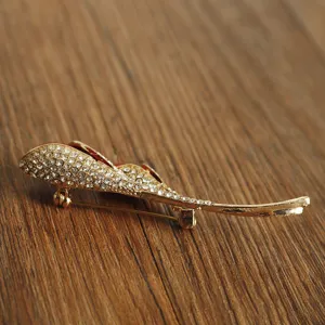 Detail shot of an elegant gold-toned rhinestone rose bud brooch on a wooden background.