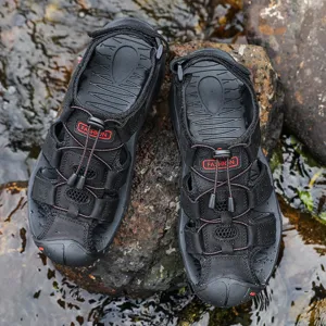 Close-up detail of black outdoor sport sandals with elastic drawstrings on wet rocks.