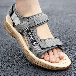 Close-up detail of men's outdoor sport sandal with grey webbing straps and tan thick sole.