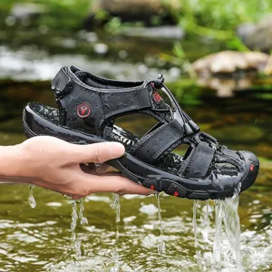 Close-up detail of black outdoor water sandals featuring secure straps and wet river backdrop.