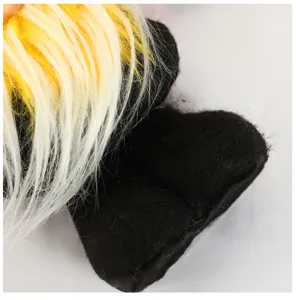 Close-up detail of cute faceless gnome plush toy with yellow hair and black feet.