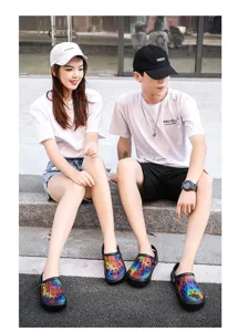 Pareja con zuecos de jardín coloridos al aire libre en escalones, foto de estilo de vida.