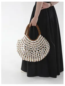 Gros plan détaillé du design de sac porté épaule ajouré en perles blanches et brunes.