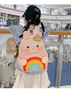 Cute pink rabbit children backpack detail showing rainbow graphic and 3D ears in mall.
