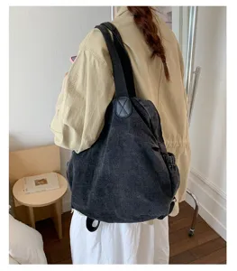 Vue détaillée du sac à dos et fourre-tout multifonction en denim lavé vintage pour le travail.