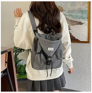 Detailansicht des grauen Canvas-Kapuzenrucksacks mit süßem Polka-Dot-Futter und Riemen.