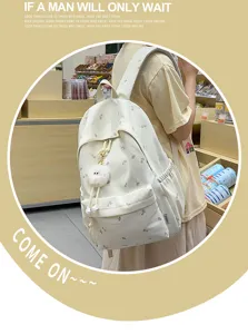 Detailansicht des beige-farbenen Rucksacks aus Leinen mit Ahornblatt-Print und Plüsch-Anhänger.