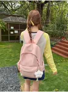 Vista di dettaglio dello zaino rosa in nylon all'aperto, con ampio spazio e grazioso ciondolo.