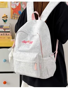Detalle de la mochila escolar gris con tirantes rosas y diseño de logotipo bordado al frente.