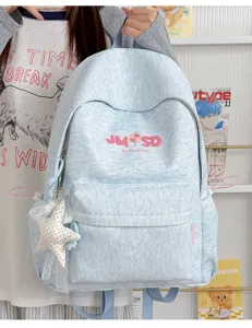 Vista detallada de mochila escolar azul claro con bordado de letras y colgante de estrella.