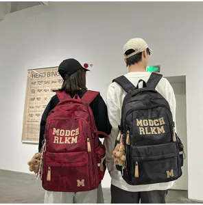 Detailed view of the large capacity camo school backpack with bear pendant and letter prints.