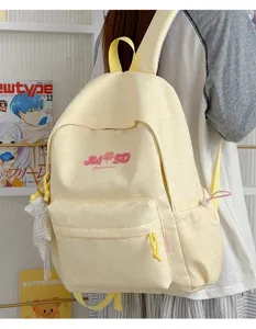 Detalle de mochila escolar amarilla con logo bordado, bolsillo delantero y correas cómodas.