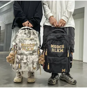 Detailed view of the large capacity camouflage student backpack with cute bear pendant and cool lettering.