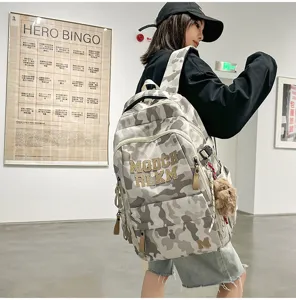 Detail view of the stylish camouflage school backpack featuring letter embroidery and bear charm.