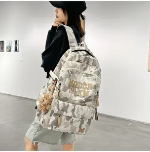 Fashionable large capacity camouflage student backpack with cute bear pendant for daily use.