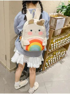 Detail view of cute cartoon animal kids backpack with colorful rainbow pattern and soft straps in store.