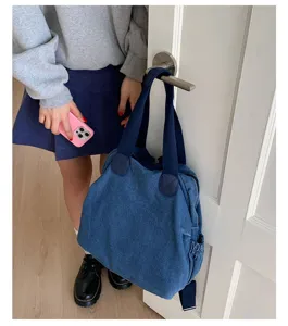 Vue détaillée du sac à dos et fourre-tout multifonction en denim lavé rétro sur une porte.