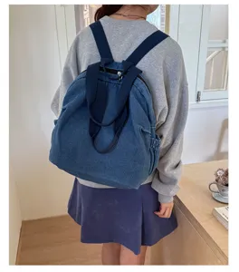 Vue détaillée du sac à dos en denim lavé vintage multifonctionnel porté par le modèle.
